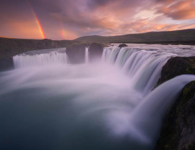 A bright rainbow shines behind the wonderful Goðafoss waterfall.