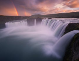 Un arc-en-ciel lumineux brille derrière la magnifique cascade de Goðafoss.