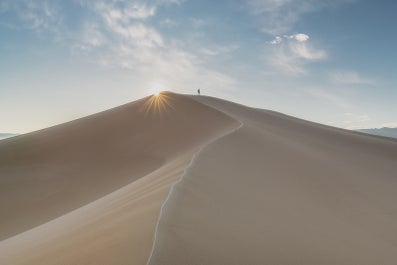 A traveler stands on an enormous dune in the Gobi Desert, Mongolia.