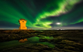 L'Aurora Borealis danse au-dessus d'un des phares d'Islande.