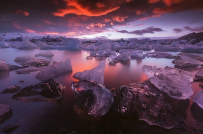 Icebergs glisten and reflect the warm colours of a sunset at Jökulsárlón glacier lagoon in the southeast of Iceland.