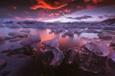 Icebergs glisten and reflect the warm colours of a sunset at Jökulsárlón glacier lagoon in the southeast of Iceland.