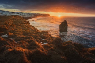 Die Sonne geht über Islands Südküste mit ihren vielen dramatischen Felsnadeln unter.