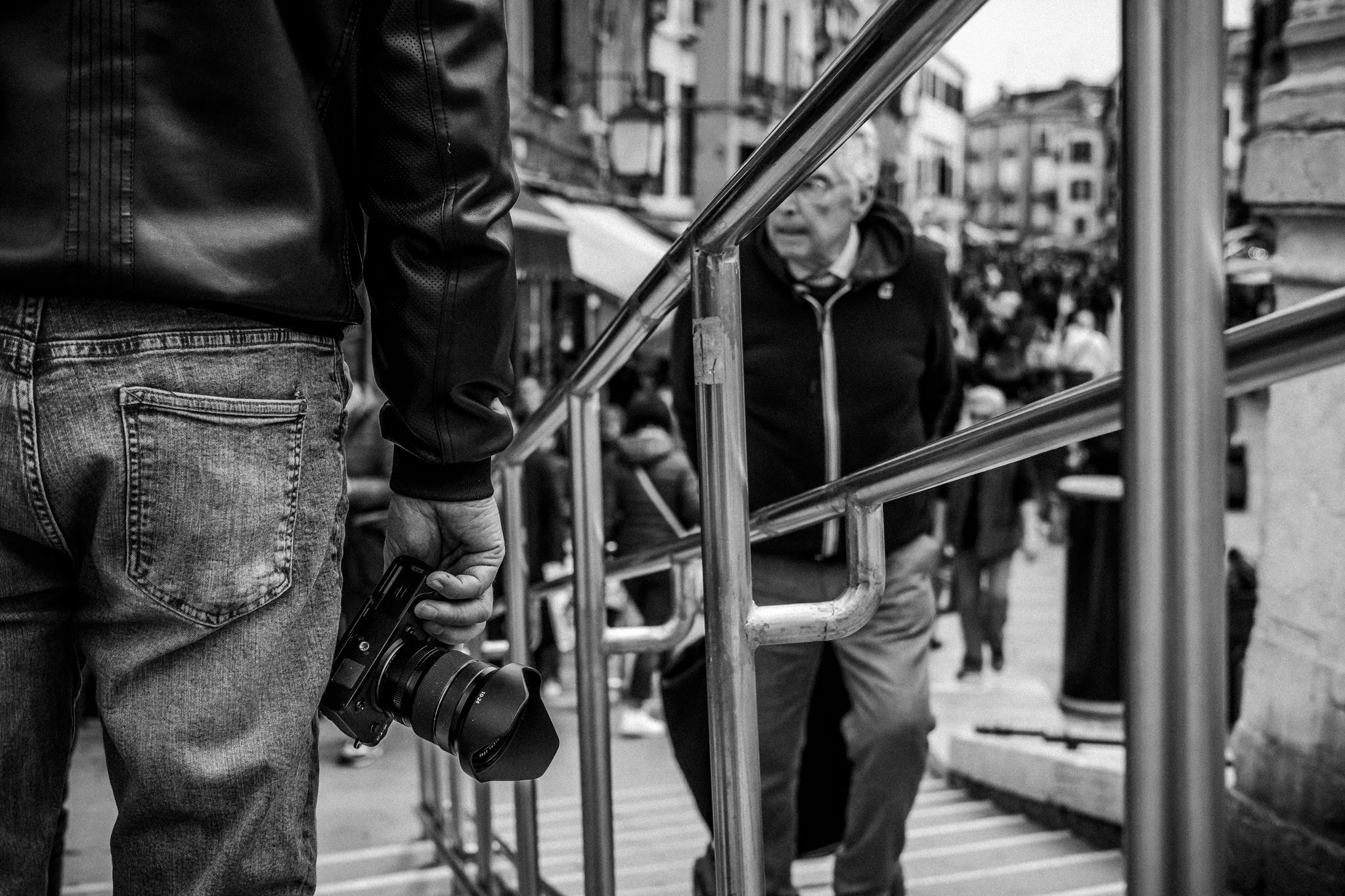 A man holding a Fujifilm camera in hand while stood in the street.