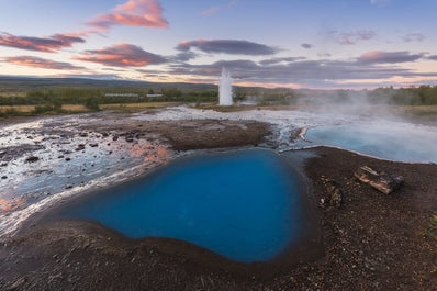 Der Strokkur speit bei Sonnenaufgang kochendes Wasser aus.