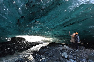 Two adventurers are captivated by the beauty of the blue ice cave.