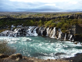 The natural beauty of Hraunfossar leaves visitors in awe as the water gracefully flows through the rugged landscape.