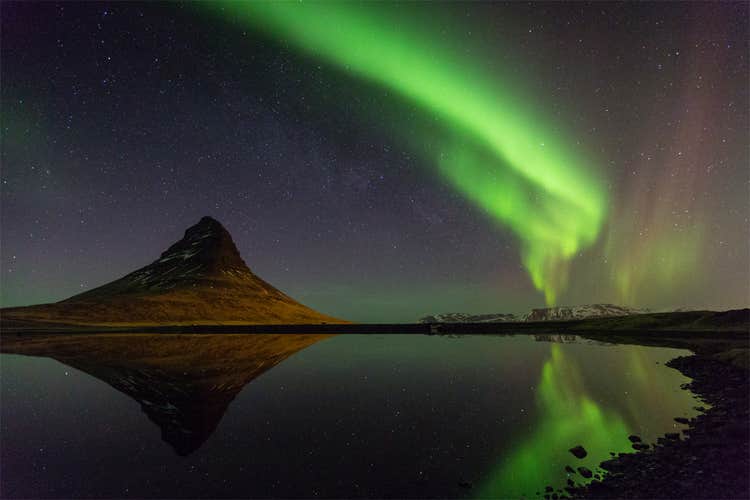 The iconic Kirkjufell mountain basks under a mesmerizing display of the northern lights, creating a truly magical sight.