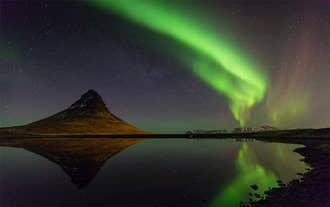 The iconic Kirkjufell mountain basks under a mesmerizing display of the northern lights, creating a truly magical sight.