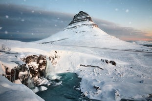 Kirkjufell mountain stands tall and majestic in a serene winter wonderland.