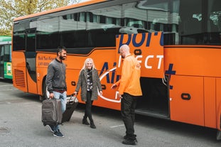 A bus staff assists travelers in loading their luggage for this bus transfer to Keflavik Airport.