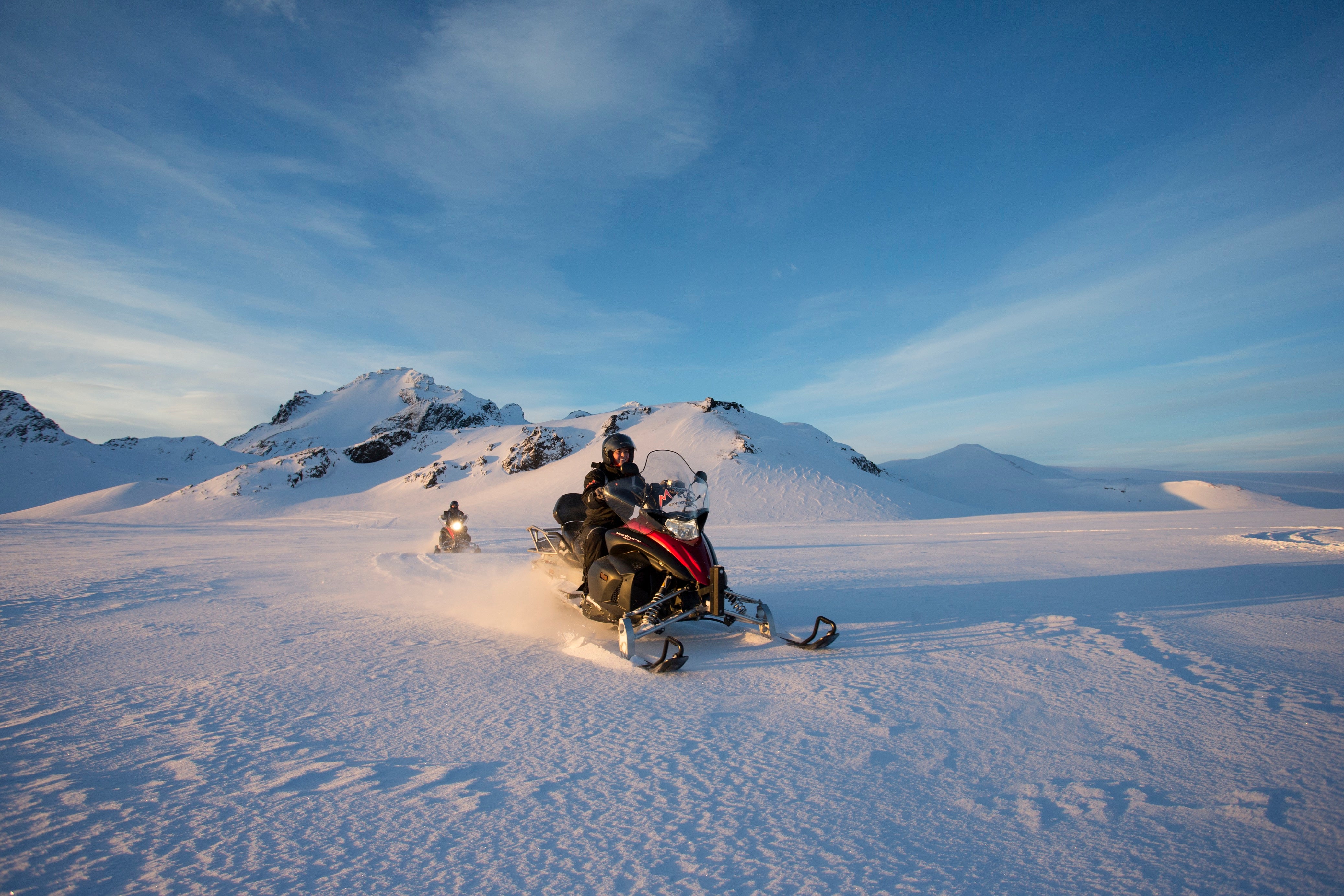 People zoom across the perfect powder of the Langjokull glacier on snowmobiles.