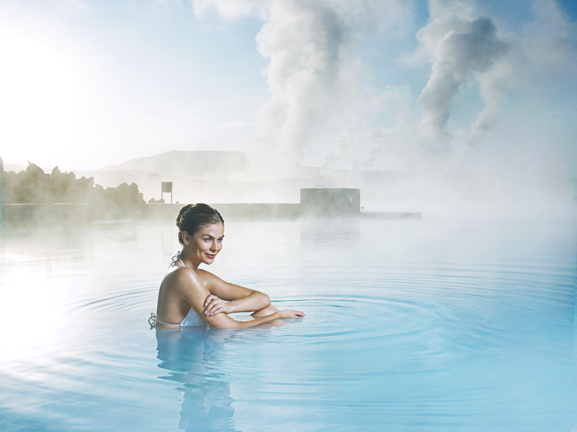 A woman leans on the edge of an infinity pool at the Blue Lagoon geothermal spa.