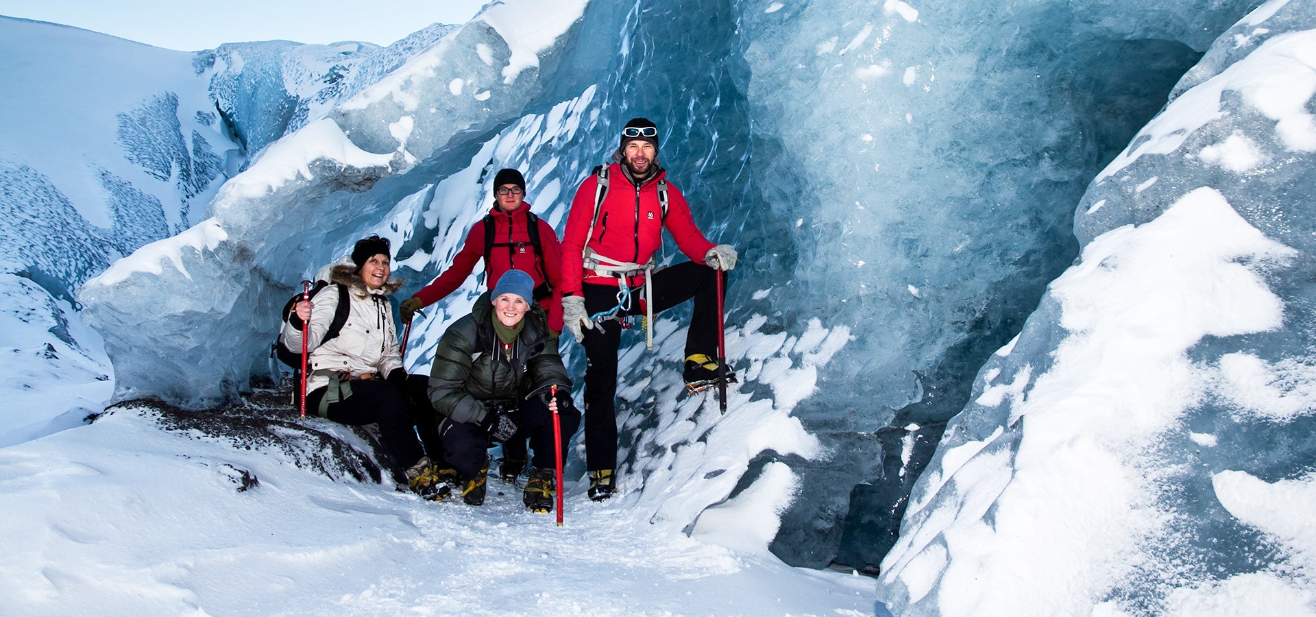 Happy people pose for a photo inside a dazzling ice formation during a guided Solheimajokull glacier hike.