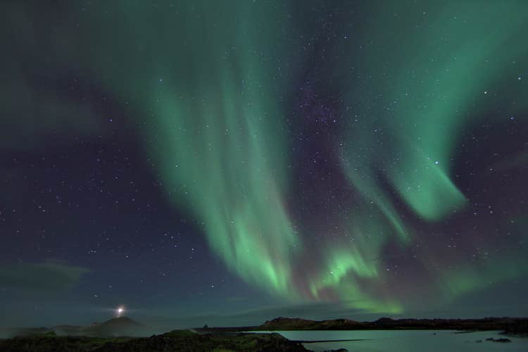 The aurora borealis lights up the starry winter night sky with an impressive painting in shades of green.