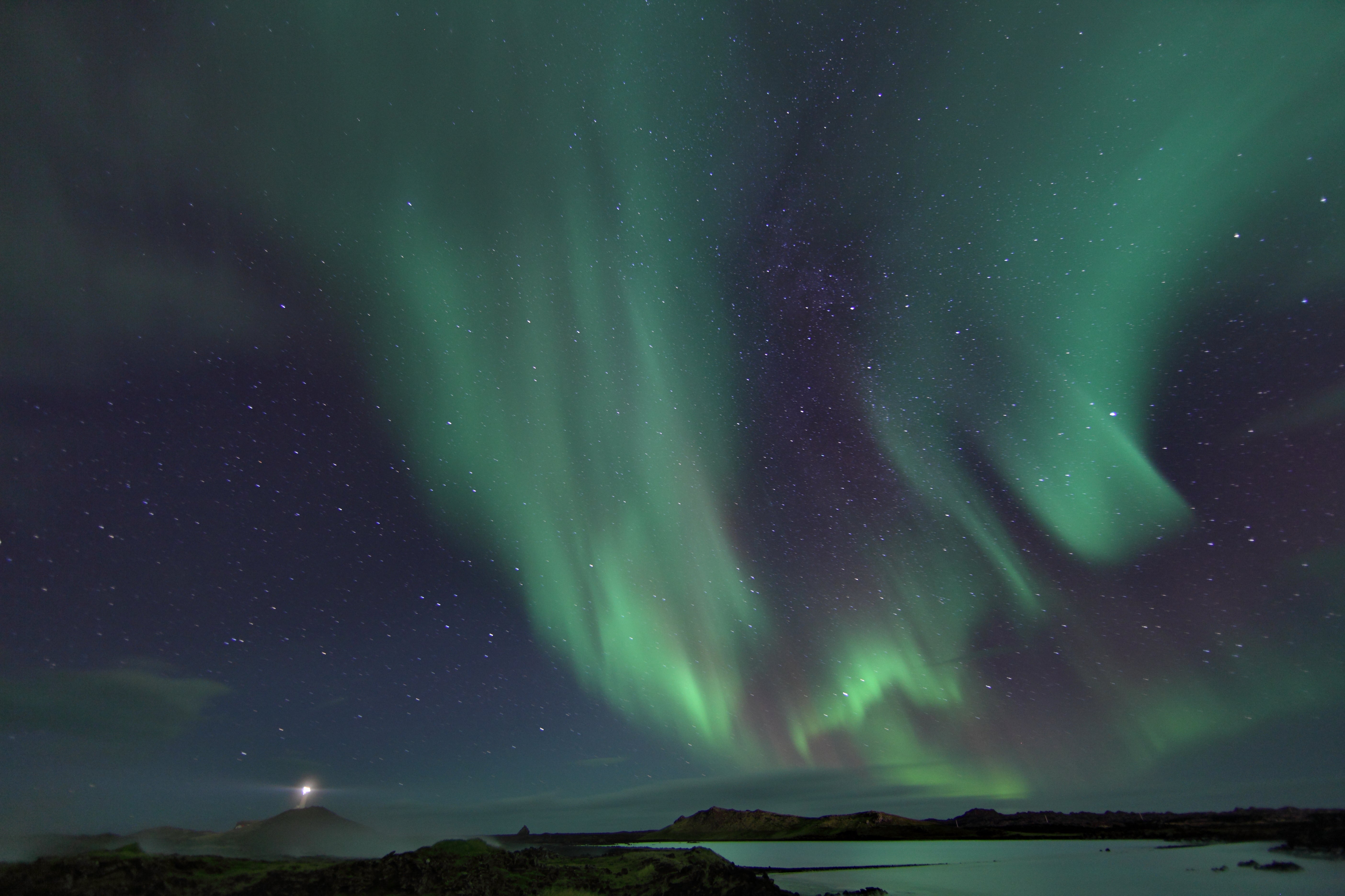 The aurora borealis lights up the starry winter night sky with an impressive painting in shades of green.