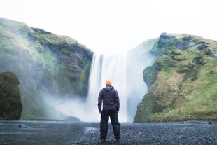 A traveler posing in front of the beautiful Skogafoss waterfall in the South Coast of Iceland.