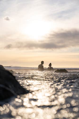 People bathe in the picturesque Sky Lagoon geothermal spa near Reykjavik at dusk.
