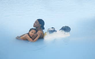 An adult and child enjoying the warmth of the Blue Lagoon geothermal spa.