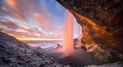 Seljalandsfoss Waterfall invites you to witness its captivating 60-meter drop and experience the unique thrill of walking behind the cascading curtain of water.