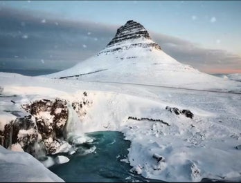 Kirkjufell Mountain stands majestic amidst a snowy wonderland.