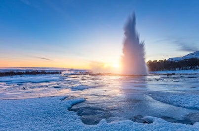 Strokkur geyser defies the cold, erupting in a spectacular display of steam and ice, a natural wonder of Iceland's icy season.