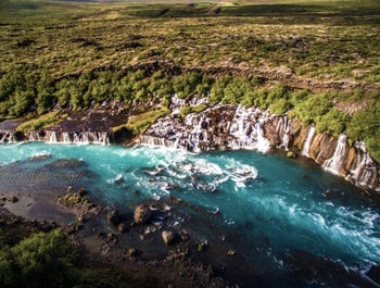 Hraunfossar reveals a mesmerizing display of countless waterfalls emerging from beneath ancient lava fields in Iceland.