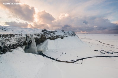 Seljalandsfoss waterfall and its surroundings are covered in a blanket of snow during winter.