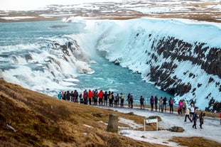 A crowd of travelers gather to admire Gullfoss waterfall in winter.