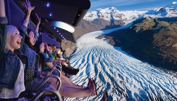 A group of adventurers takes flight in front of a glacier simulation at FlyOver Iceland.