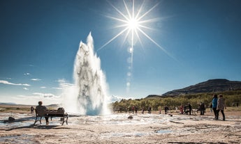 Travelers watch in awe as Strokkur geyser erupts with boiling water in Geysir area.