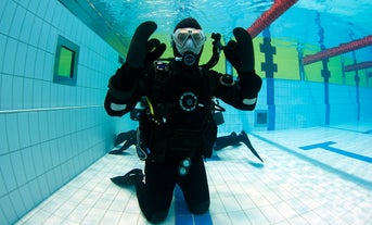 A dry suit diving student photographed under an indoor pool in Reykjavik.