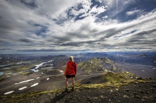 A hiker stands on a peak in the Icelandic Highlands, looking across at the breathtaking landscape.