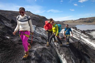 Happy people explore the rugged landscape around the Solheimajokull glacier.