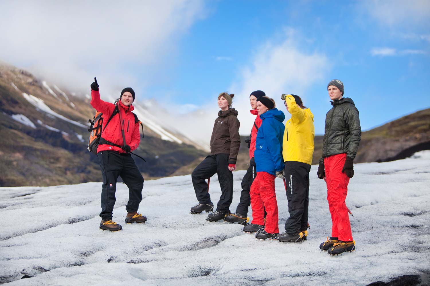 An expert guide points to something during a glacier tour at Solheimajokull.