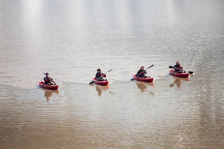 A line of kayakers paddle across the tranquil waters of the Solheimajokull glacier lagoon.