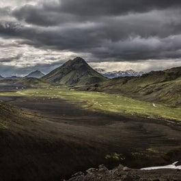 A striking volcanic landscape in Iceland with dramatic peaks and contrasting hues of black and green.