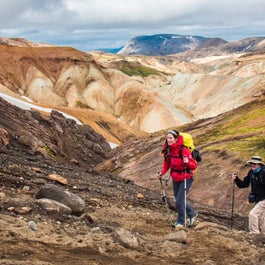 People hike amid colorful rhyolite mountains in the Icelandic Highlands.