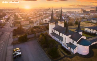 Hateigskirkja church in Reykjavik with the city behind it at sunset.