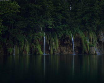 Water streams down a dark cliff in Plitvice Lakes National Park.